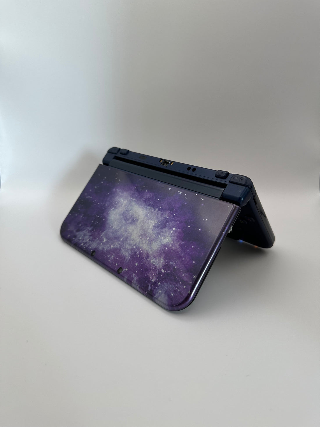 ReCollected New Nintendo 3DS XL handheld console featuring a purple and blue galaxy nebula pattern on the outer shell.