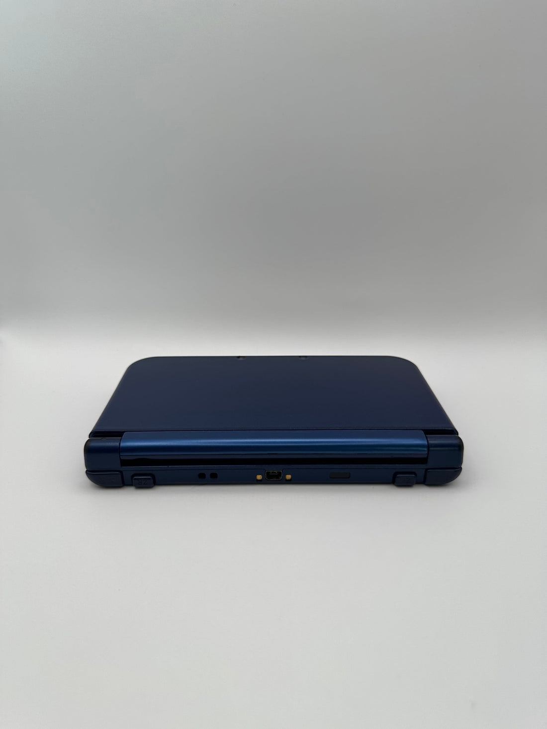 ReCollected New Nintendo 3DS XL in Blau, zusammengeklappt, von hinten gesehen, inklusive Ladeanschluss.