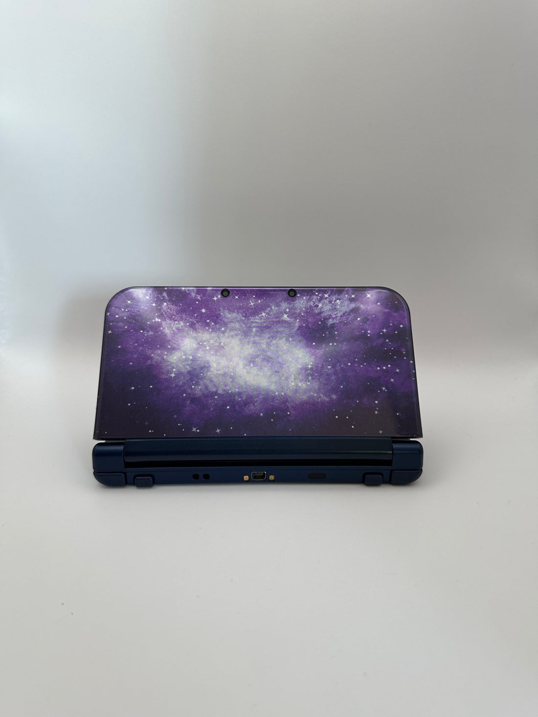 ReCollected New Nintendo 3DS XL handheld console featuring a purple and white galaxy space pattern on the top shell