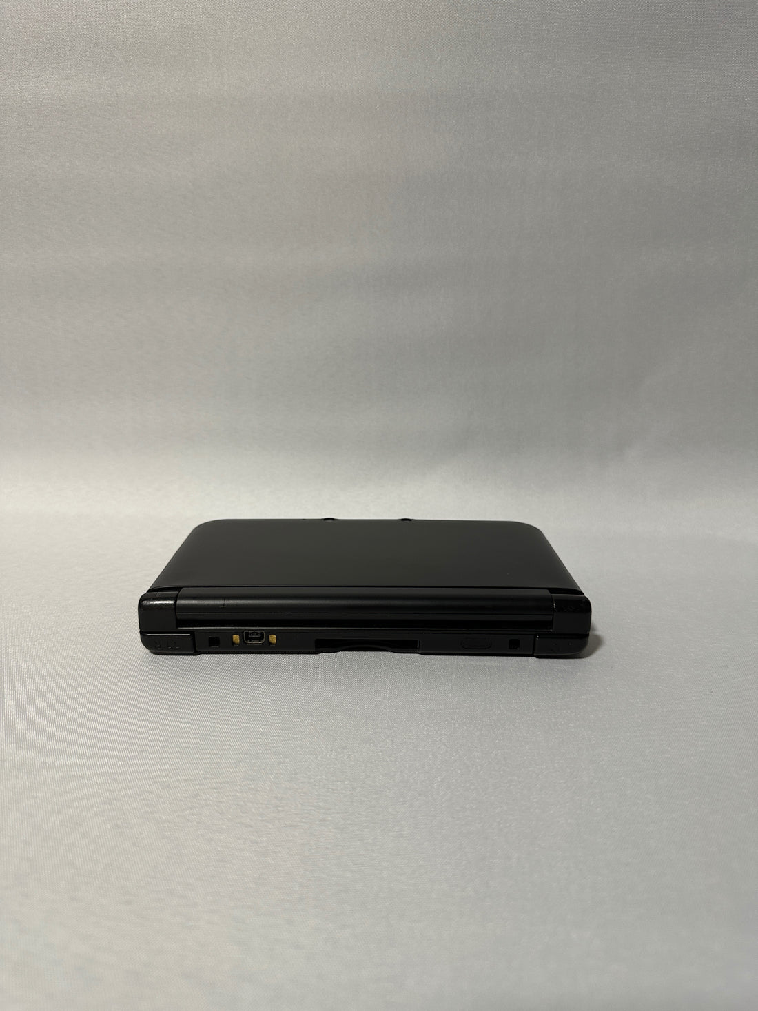 ReCollected New Nintendo 3DS XL Konsole in Schwarz, zugeklappt auf grauem Hintergrund
