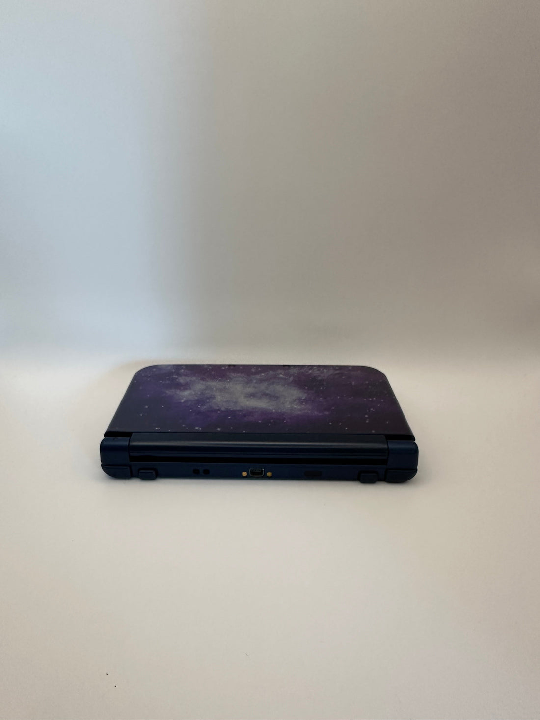 ReCollected New Nintendo 3DS XL handheld console in a purple and blue galaxy space print, closed view.