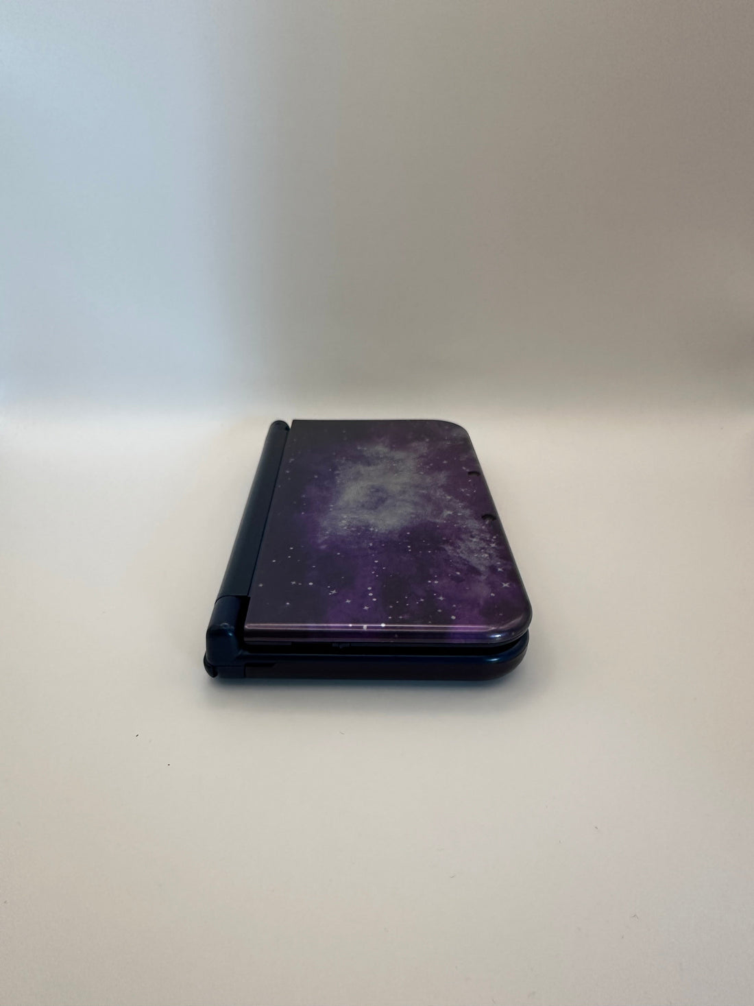 ReCollected New Nintendo 3DS XL handheld console in a purple galaxy space print, closed view.