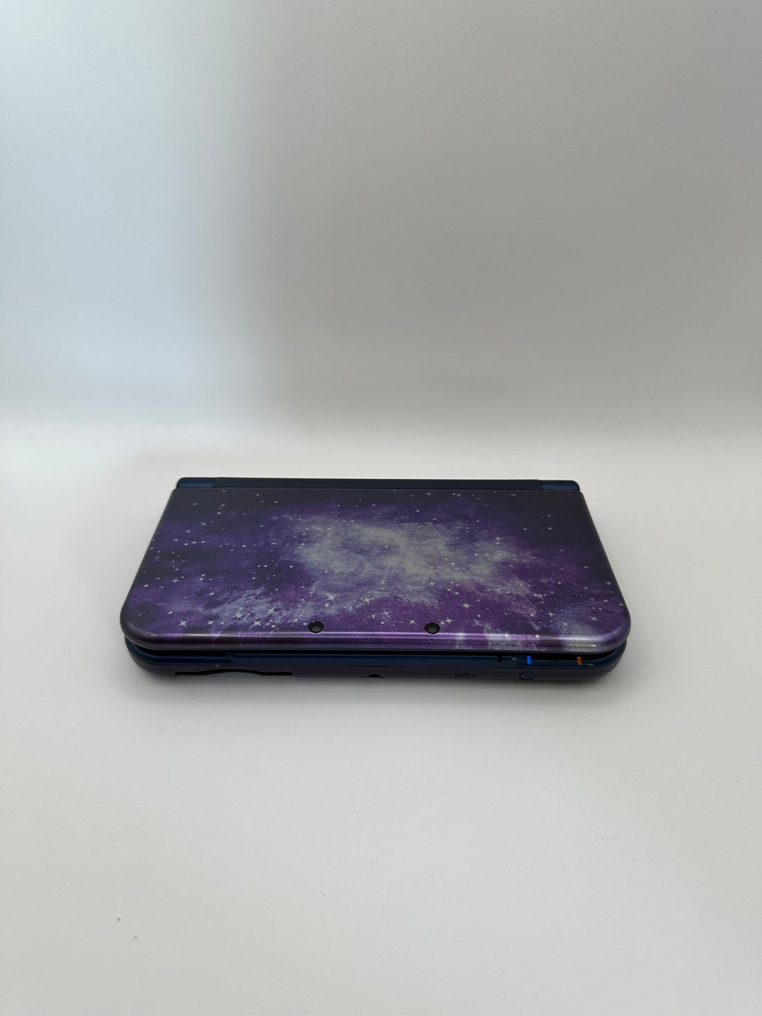 ReCollected New Nintendo 3DS XL handheld gaming console in a purple galaxy space print, closed view.